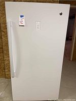 Front view of the white upright freezer showing door and handle