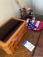 View showing burled wood humidor, synthetic American flag, and two wooden carved decorative items on a wooden surface