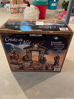Photo of sealed Kirkland 13-piece nativity set in retail box showing the front with the stable and all figures displayed.