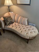 Full view of warm beige velvet chaise lounge with tufted design and decorative pillow on top