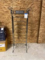 Front view of tall metal Kendall Jackson wine rack showing multiple wave-shaped racks for wine bottles and the scrolled towel holders at top.