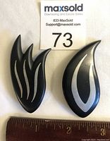 Two Hans Hansen brooches side by side, one with fire flame design and one teardrop shaped, measured next to a ruler for scale.