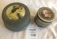 Overview of both vintage jewellery music boxes on a white cloth background with lot number card