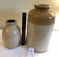 Two pottery jars displayed with ruler for scale, front view showing size and shape differences.