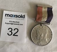 Front view of a silver-colored 1937 coronation medal featuring King George VI and Queen Elizabeth with original ribbon in tri-color red, white, and purple.