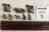 Top-down view of 12 small metal animal figures arranged in two rows next to ruler for scale showing measurements from 0.5" to 1" height.