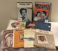 Partial view of various vintage sheet music covers including 'Wishing Ring' and 'High Society Blues'