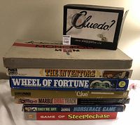 Stack of eight vintage board game boxes including first edition Cluedo, Monopoly, The Inventors, Wheel of Fortune, Marble Drag Track, Horse Race Game, and Game of Steeplechase.
