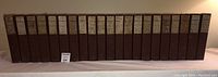 Front view of all 21 brown hardcover volumes of the Works of Voltaire 1901 set, showing uniform size and spine labels.
