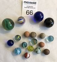 Top-down view showing 18 marbles including green marble, cobalt blue marbles, a multicolored onion skin marble, several stone-like marbles, and various colored glass marbles.