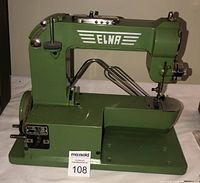 Side view of the green Elna Grasshopper sewing machine showing the Elna logo, hand wheel, and fold-out wire arm stand.