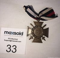 Front view of the WW1 Hindenburg Cross medal showing the 1914-1918 inscription and tri-color ribbon attached.