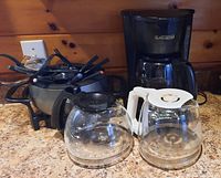 Front view of Black and Decker coffee maker with two additional coffee pots in front and Rival electric fondue pot behind