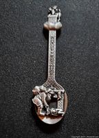 Front side of 1992 Harley Davidson pewter collector spoon showing detailed raised design of blacksmith figure and Harley Davidson name on handle.