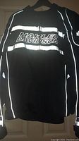 Front view of the black riding jacket with large silver reflective stripes and Harley-Davidson lettering on the chest.