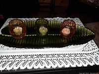 Full view of the green glass tray and three colored glass candle holders on top, each with an inner white candle-shaped piece.