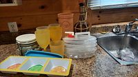 Photo of terracotta wine cooler, plastic wine glasses, decorative decanter, citrus-themed plastic plates, and plastic containers