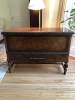 Full front view of chest showing hinged top lid, lower drawer, carved trim and turned legs