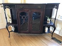 Full view of antique wooden hutch showing two glass cupboard doors, lattice work side shelves and carved drawer.