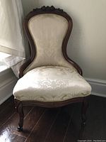 Full frontal view of the antique slipper chair showing wood frame and upholstery.