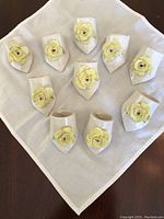 Top-down view of all ten ceramic napkin rings arranged on a linen napkin.