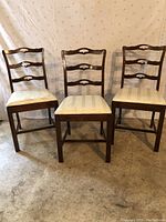 Front view of three wooden breakfast/dining chairs with upholstered seats showing wear on the fabric and wooden frames in good condition.