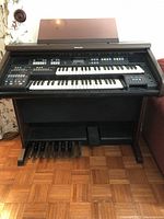Full view of the Technics electric organ showing the two keyboards, pedalboard, and music stand.