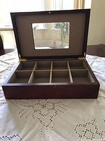 Open wooden tea caddy box showing 8 compartments with fabric lining and interior details.