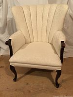 Front view of white upholstered wingback chair showing vertical channel tufted back and floral patterned fabric.