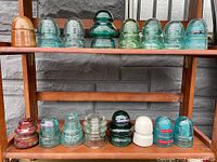 Wooden display shelf with two rows of assorted glass and porcelain insulators