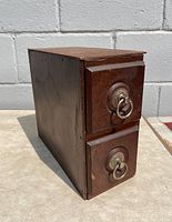 Side angled view of the antique sewing cabinet drawer showing wood grain, dovetail joinery, and metal hardware on two drawers.