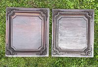 Pair of antique wooden doors lying on grass showing decorative corner carvings and recessed panel design, front view.
