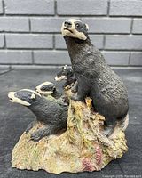 Front angled view of Aynsley hand painted badger family figurine showing the four badgers on textured forest base.