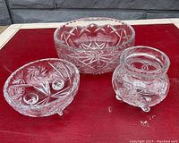 Three vintage cut crystal bowls displayed on red surface showing various intricate cut designs and details