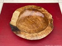 Top view of oval live edge wooden bowl showing natural wood grain and imperfections on red background.