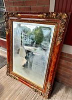 Full view of the large ornate mirror showing its rectangular shape and elaborate frame with detailed floral and leaf designs.