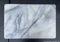 Top view of rectangular white marble cutting board with dark gray veins.