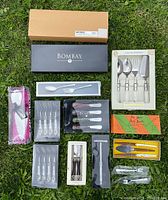 Overview of various boxed Bombay cutlery sets arranged on grass, including servers, forks, knives, and specialty utensils.