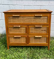 Front view of Pier One dresser showing five drawers with bamboo accents and solid wood frame, placed outside on grass.