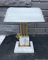 Front view of the bankers desk lamp showing white glass shade, marble base with brass inset, and brass rods.
