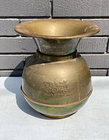 Front view of vintage brass spittoon with embossed Union Pacific train logo and patina.