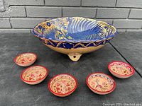 Large vintage ceramic fruit bowl featuring blue, gold, and yellow intricate floral patterns and three small feet.