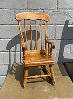 Front view of the vintage solid wood kids rocking chair showing spindle back and curved armrests