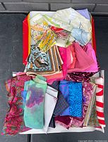 Box containing folded vintage ladies silk scarves of various colors and patterns, displayed from a top view.