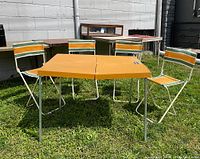 Pop-up picnic set fully assembled with table and four matching chairs outdoors on grass.