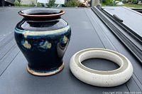 Photo showing dark blue glossy pot and separate off-white circular ceramic decorative piece.