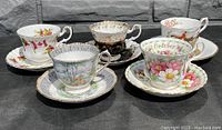All five vintage Royal Albert cups and matching saucers displayed in sunlight showing pattern and condition
