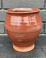 Front view of vintage signed terracotta clay pot showing glossy brown glaze on upper portion and unglazed bottom.