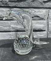 Clear Murano glass dolphin sculpture on bubble base, showing side profile with dolphin leaping right and balanced on bubble with internal bubbles.