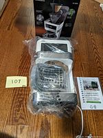 Braun BrewSense KF 6050 coffee maker wrapped in plastic with instruction manual and box in background, placed on wooden floor.